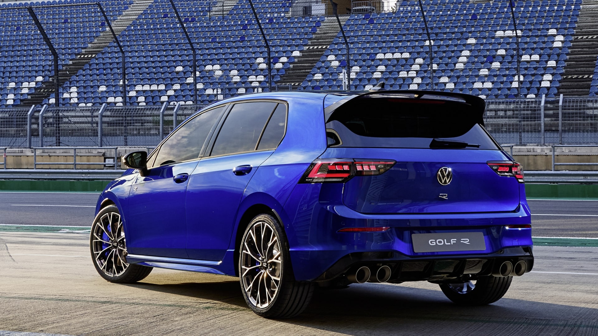 Rear view of a blue Volkswagen Golf R parked in a racetrack pit area.