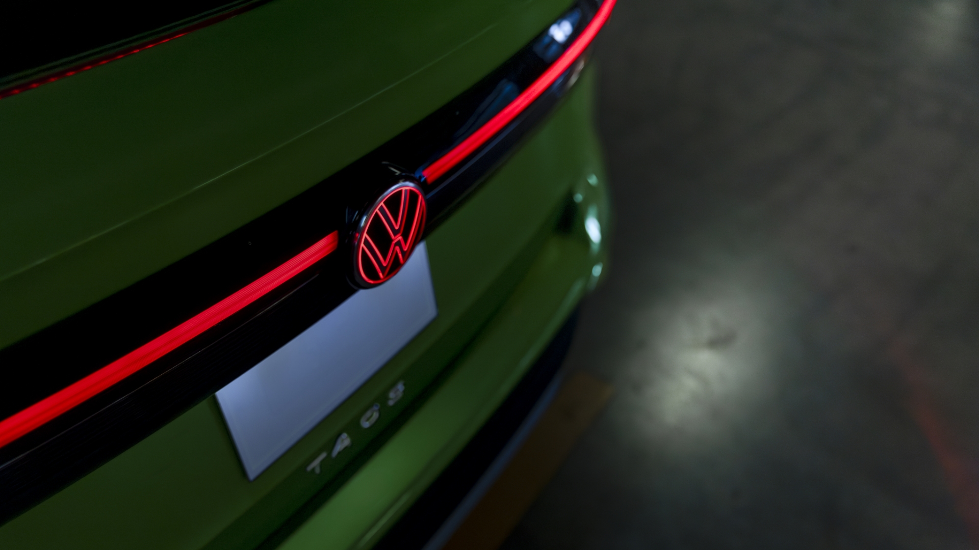 A close-up view of the green Taos 2025 illuminated LED rear light bar with the Volkswagen logo, emphasizing the modern design.