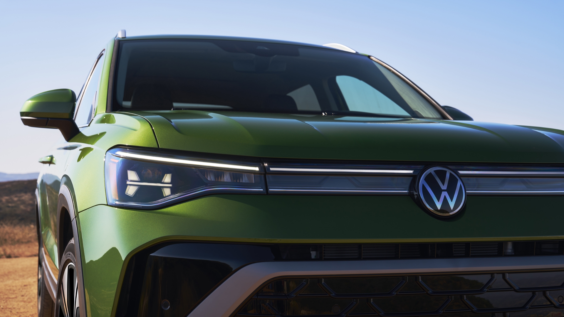 A close-up of the redesigned Taos 2025, showcasing its new front fascia and fresh interior color options, highlighting its vibrant green finish.