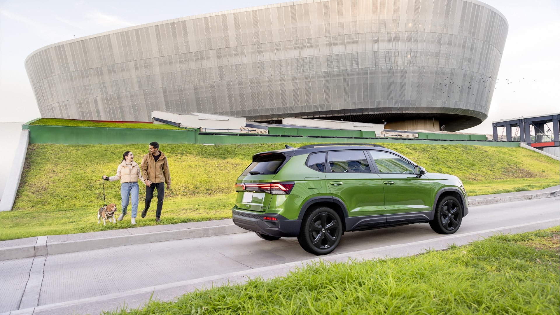 The green Taos 2025 parked outdoors, with a couple of people remotely starting the vehicle using a key fob or app.