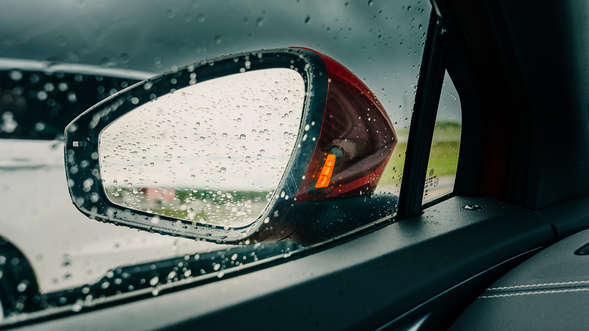 A VW car's driver-side auto-dimming side view mirror in use at night.