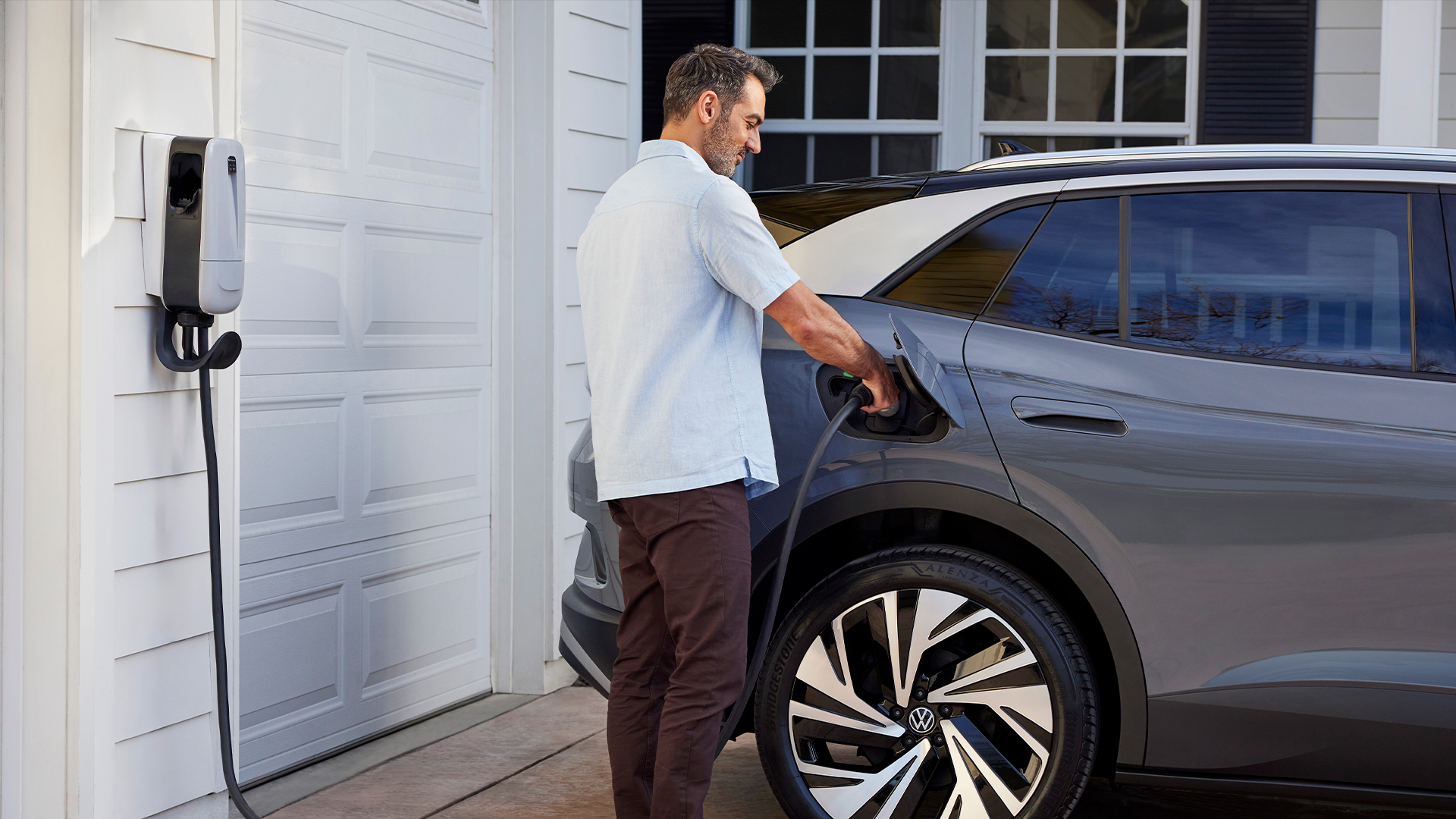 A man charging his grey 2024 VW ID.4 at home